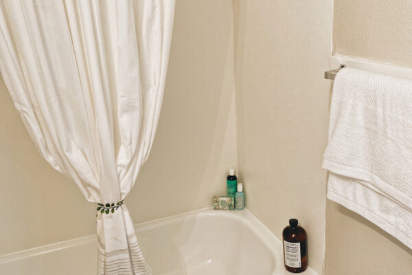 Model bath tub with a hanging towel and shower curtain that is tidy - University Trails Prairie View Student Housing