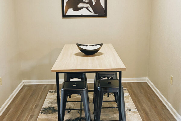 Model unit with dining Table, chairs with artwork on the wall with carpets - University Trails Prairie View Student Housing